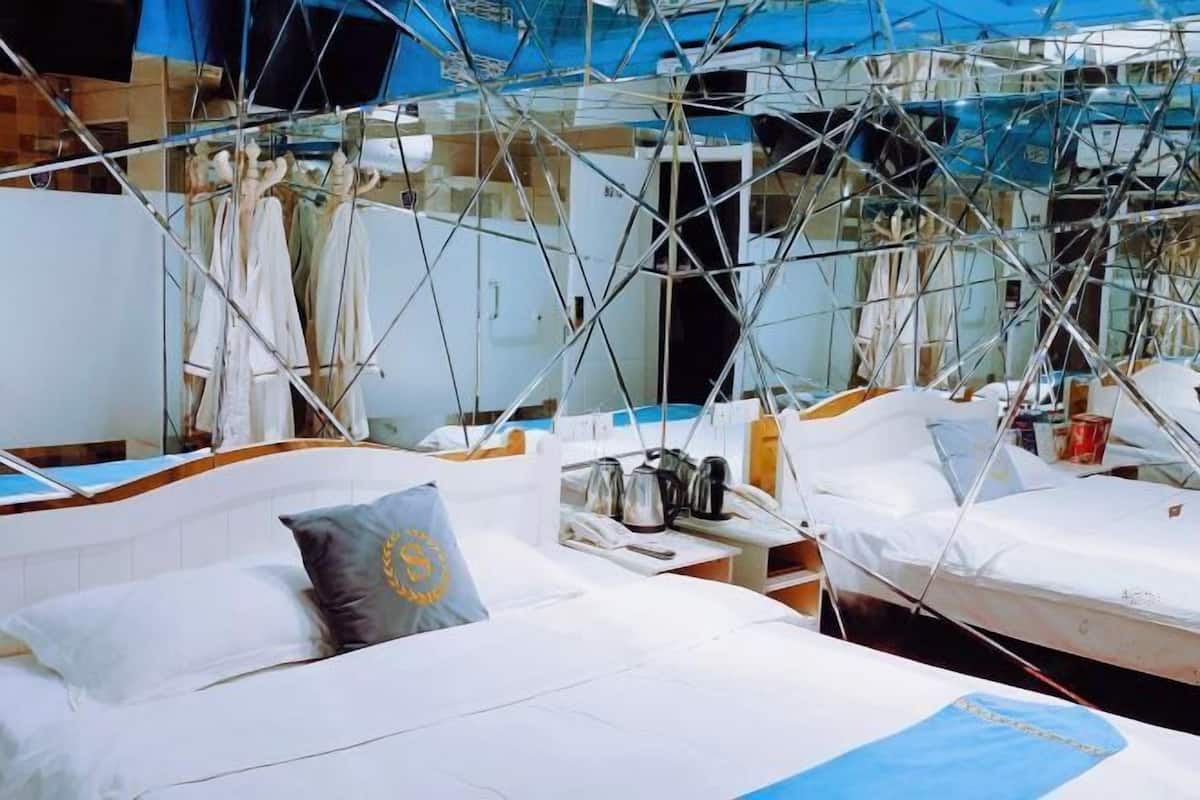 A hotel room with a bed, a pillow, a nightstand, and a window.