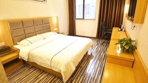 A hotel room with a bed, bedside table, a desk, a chair, a potted plant, and a window with curtains. - Kaiyue Hotel (Wuhan Vanke Emerald Binjiang) (Wuhan)