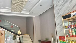 A hotel lobby with a staircase, a marble wall, and a shelf with canned goods. - Kaiyue Hotel (Wuhan Vanke Emerald Binjiang) (Wuhan)