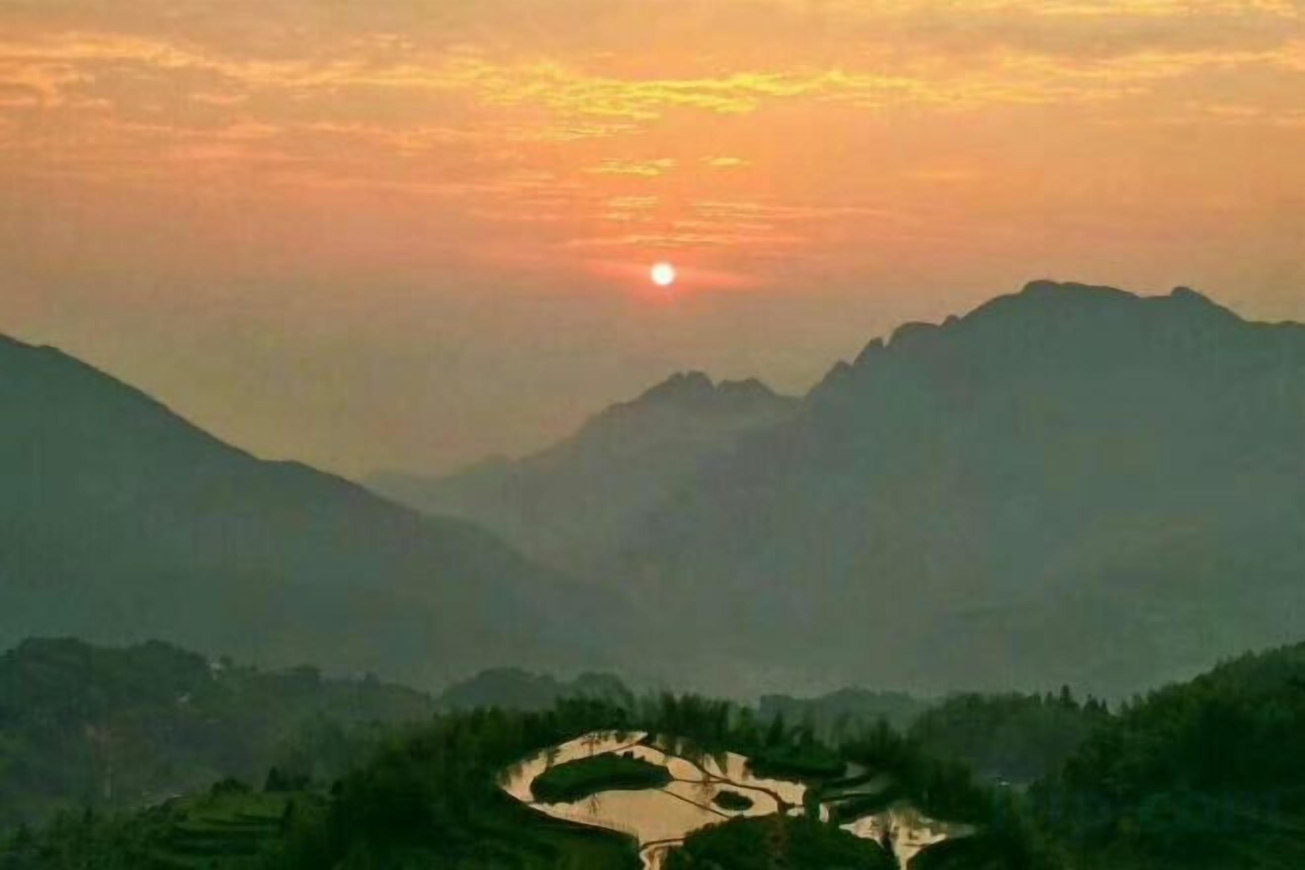 A mountainous landscape with a winding river and a sunrise or sunset.