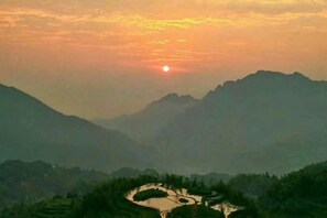 A mountainous landscape with a winding river and a sunrise or sunset.