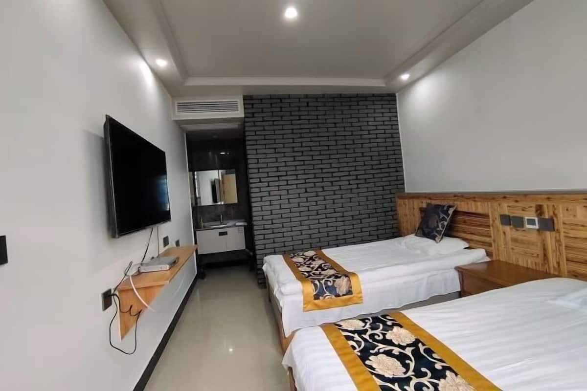 Ein Hotelzimmer mit zwei Betten, einem Fernseher, einem Holzkopfende und einer Wand mit Ziegelmuster.