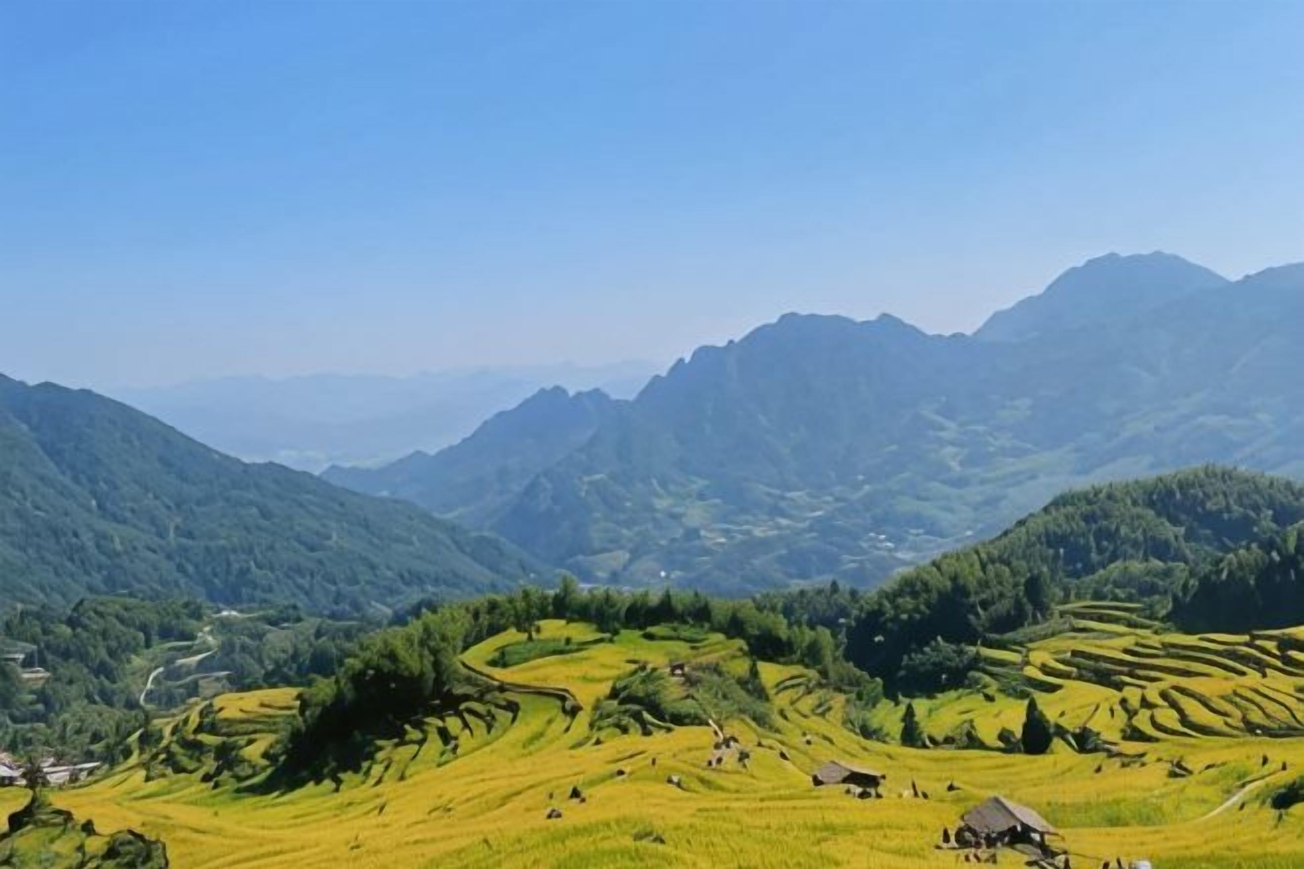 Paisaje montañoso con campos en terrazas y cielo despejado.