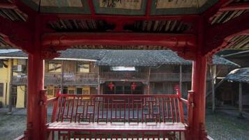 Un edificio tradicional japonés con estructura de madera roja, un balcón con barandilla y vistas a la arquitectura circundante.