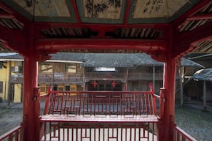 En traditionell japansk byggnad med en röd träkonstruktion, en balkong med ett räcke och utsikt över den omgivande arkitekturen.