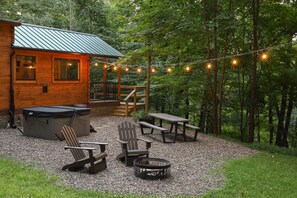Eine Holzhütte mit einer Terrasse, Sitzgelegenheiten im Freien und einer Feuerstelle.