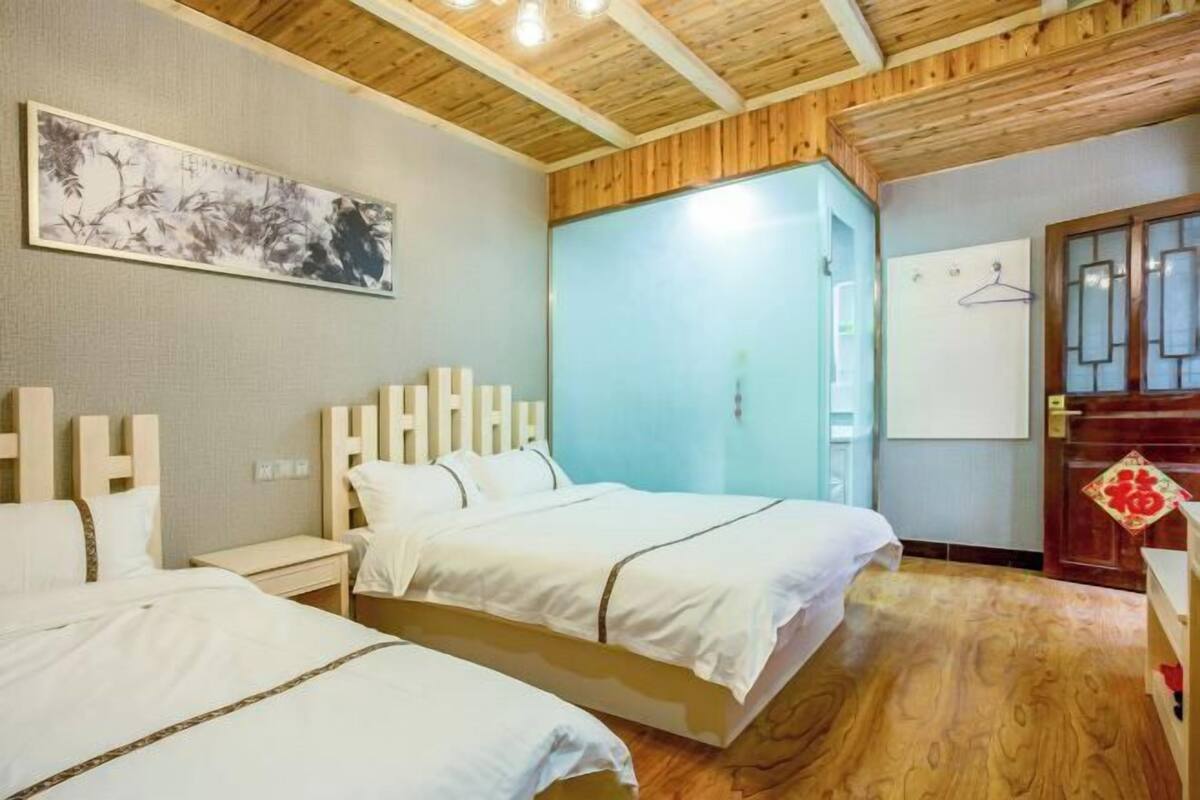 A hotel room with two beds, a wooden ceiling, a painting on the wall, and a wardrobe.