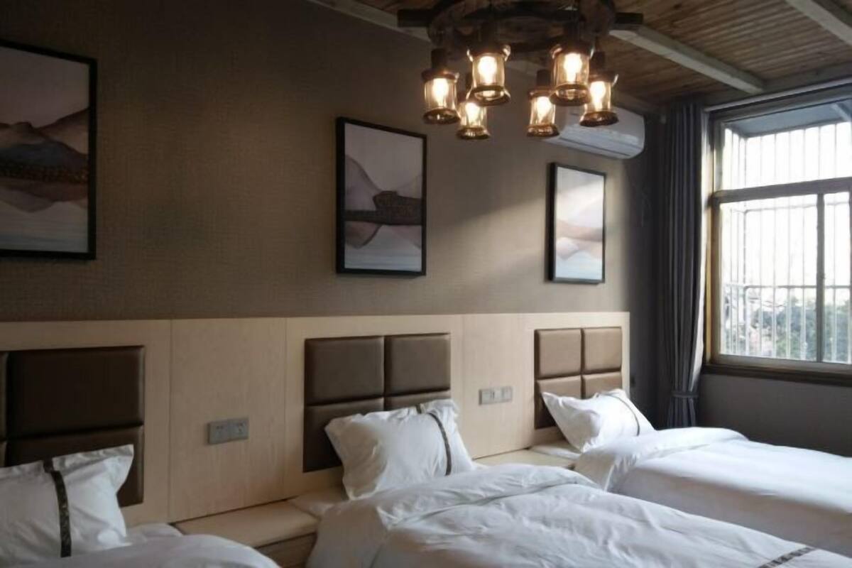 A hotel room with two beds, a wooden ceiling, and artwork on the walls.
