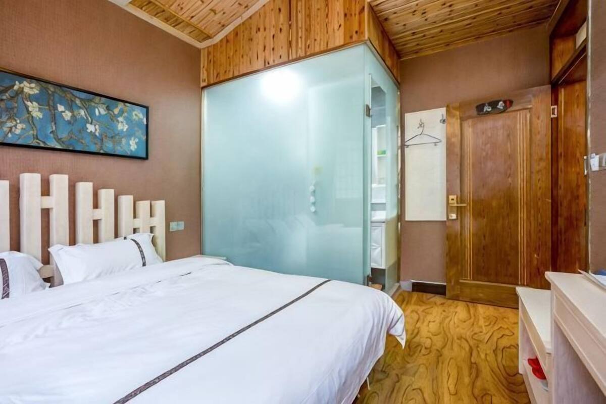 A bedroom with a bed, a wardrobe, a mirror, and a painting on the wall.