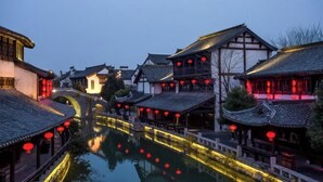A traditional Chinese courtyard with buildings, a water canal, and red lanterns. - Anyu · Wooden House (Zaozhuang)