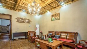 A wooden-floored living room with a sofa set, a coffee table, and a chandelier. - Anyu · Wooden House (Zaozhuang)