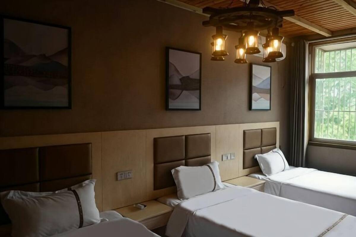 A hotel room with two beds, a wooden ceiling, and artwork on the walls.