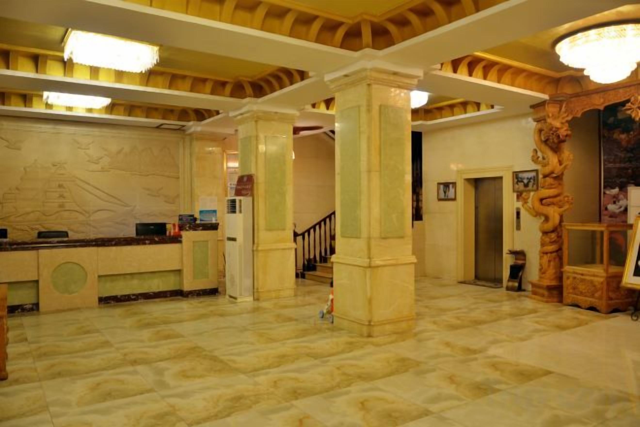 A lobby with marble flooring, a reception desk, and a staircase.