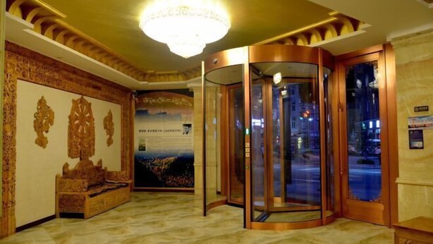 A lobby with a chandelier, a wooden bench, and a glass elevator.