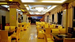 A banquet hall with rows of yellow chairs, a large screen, and a chandelier.