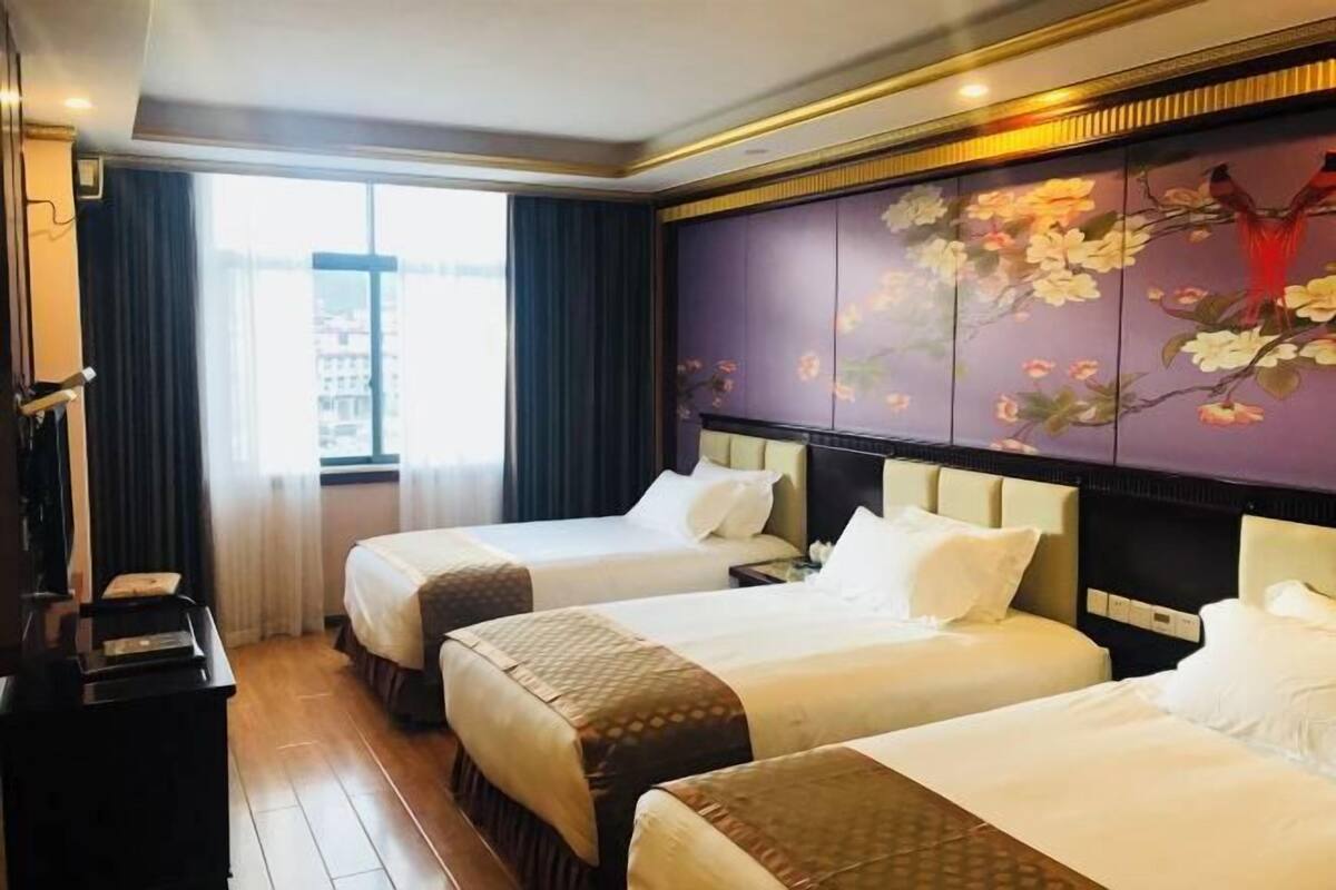 Habitación de hotel con dos camas, un escritorio y un ventanal grande.