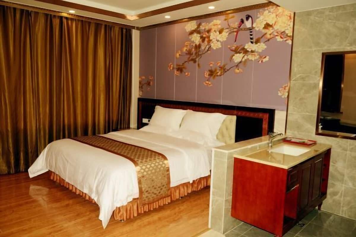 Una habitación de hotel con una cama grande, un tocador con espejo y un diseño floral en la pared.