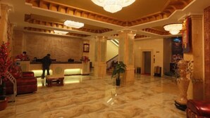 A spacious lobby with marble flooring, a reception desk, and a chandelier.