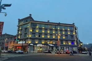 Un hotel de varios pisos con un estilo arquitectónico tradicional, que cuenta con locales comerciales en la planta baja y habitaciones en los pisos superiores.