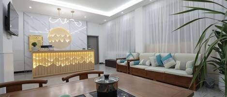 A modern living room with a sofa, a dining table with teapots, and a kitchen area with a counter.