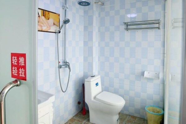 Casa de banho com sanita, chuveiro e um sinal vermelho na parede.