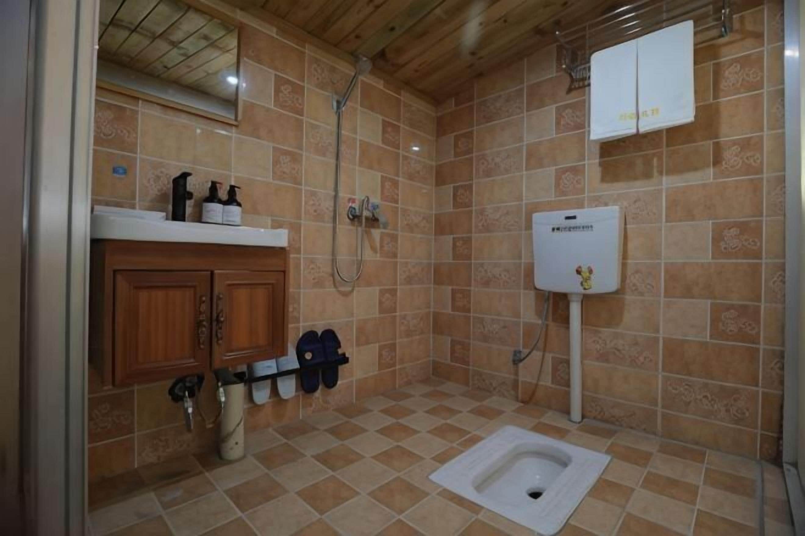 Een badkamer met douche, toilet en wastafel.