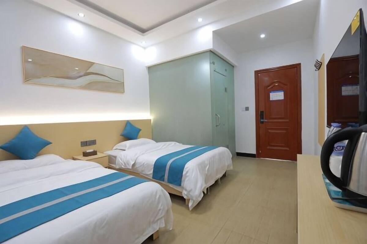 A hotel room with two beds, a wardrobe, a door, and a mirror.