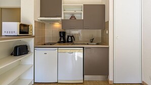 Cocina compacta con microondas, cafetera y lavavajillas.