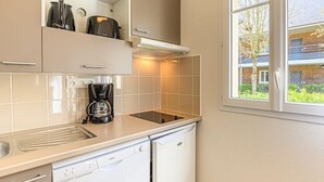 A compact kitchen with a dishwasher, a coffee maker, and a toaster on the countertop. - T2 de charme dans la cité des peintres (Pont-Aven)