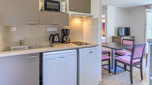 Una cocina compacta equipada con lavavajillas, microondas y cafetera. Cuenta con un comedor con mesa y sillas.