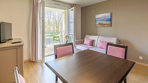 Una habitación con una mesa de comedor, un sofá, un televisor y un cuadro en la pared.