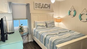 Een slaapkamer met een bed, een bureau, een raam en een plafondventilator.