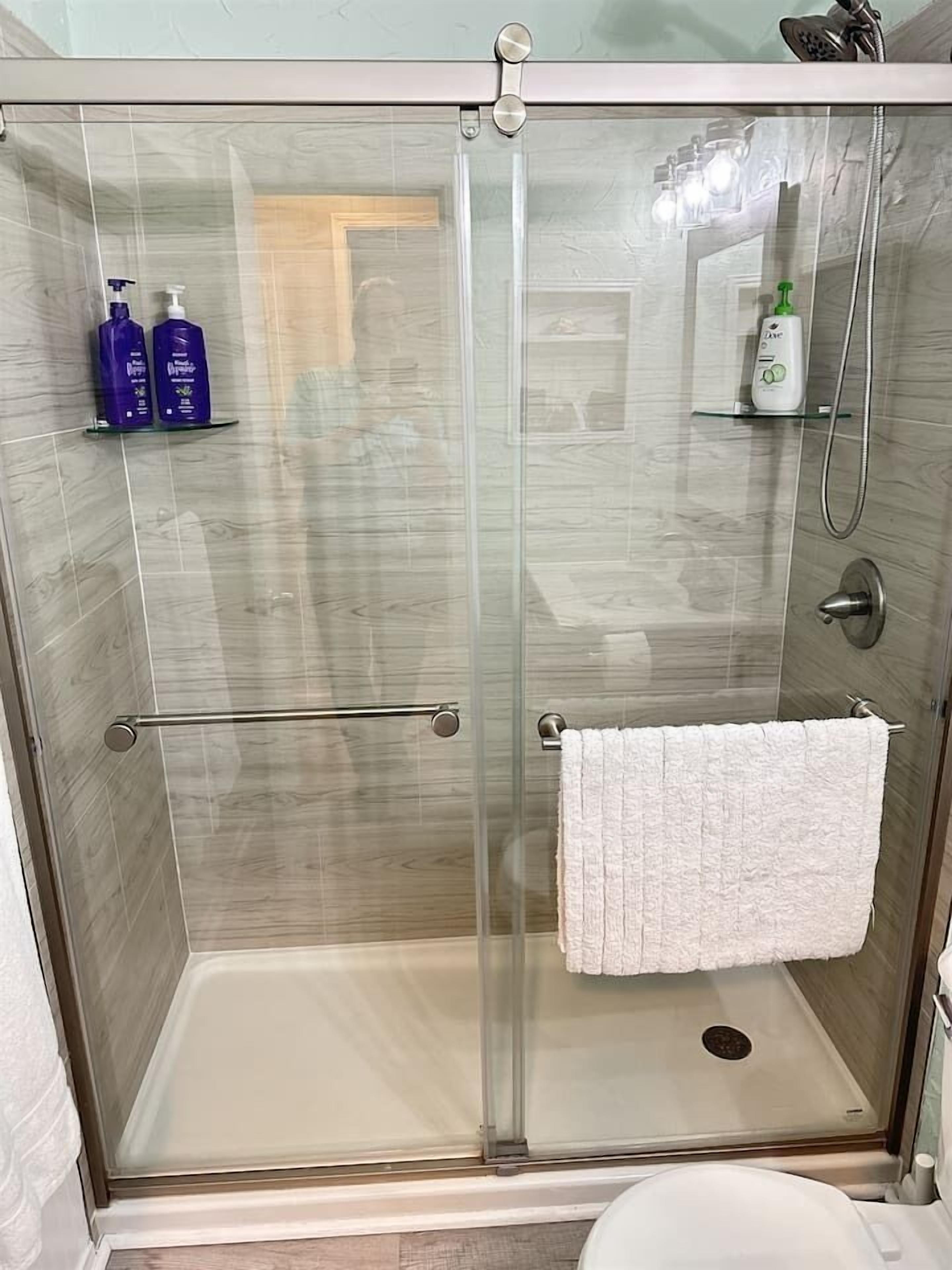 A glass-enclosed shower stall with a white towel hanging on the door.