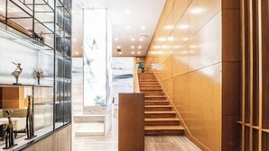 Een modern interieur met een houten trap, een glazen balustrade en een marmeren vloer.
