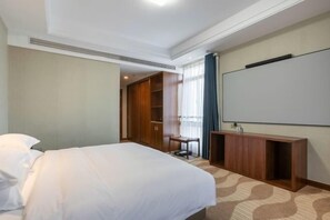 A hotel room with a bed, a desk, a wardrobe, and a television.