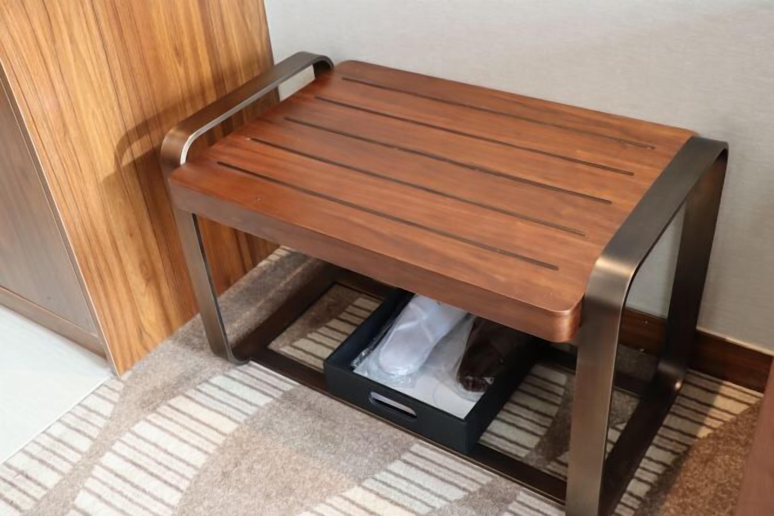 Een houten bijzettafeltje met een lade, geplaatst tegen een muur.