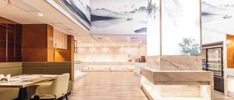 A modern restaurant with a high ceiling, wooden flooring, and a central marble counter.