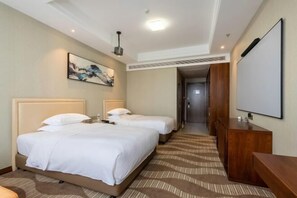 Habitación de hotel con dos camas, un escritorio de madera, un televisor de pantalla plana y un cuadro en la pared.