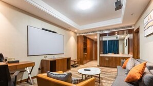 Een hotelkamer met een groot bed, een bureau, een stoel, een bank, een televisie en een kledingkast.