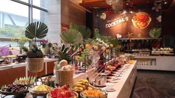 A buffet with various food items and a sign for 'Sumo's Cocktails'.