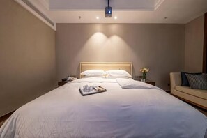 A hotel room with a large bed, a bedside table with a lamp, a nightstand, and a sofa.