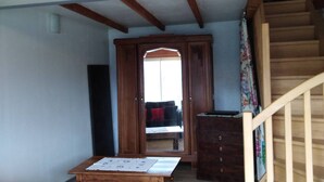 Ein geräumiger Wohnbereich mit einer Holztreppe, einem Sofa, einem Tisch und einem Kleiderschrank.