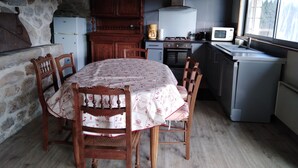 Eine kompakte Küche mit Esstisch, Stühlen, Kühlschrank, Herd, Mikrowelle und einem Fenster.