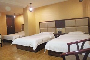 A hotel room with three single beds, wooden flooring, a large padded headboard, and a small bedside table with a lamp. - Xishui Songxuan Clubhouse Inn (Xishui)