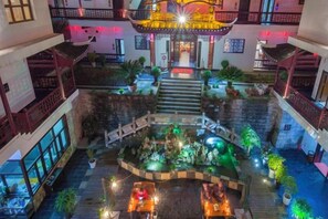A multi-level hotel atrium with a central staircase, indoor plants, and a decorative fountain. - Biancheng Gushi Theme Culture Hotel (Yongshun)