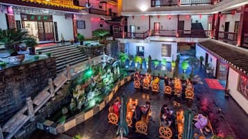 Un patio tradicional con una fuente central, escalones de madera y un espacio de descanso con sillas.