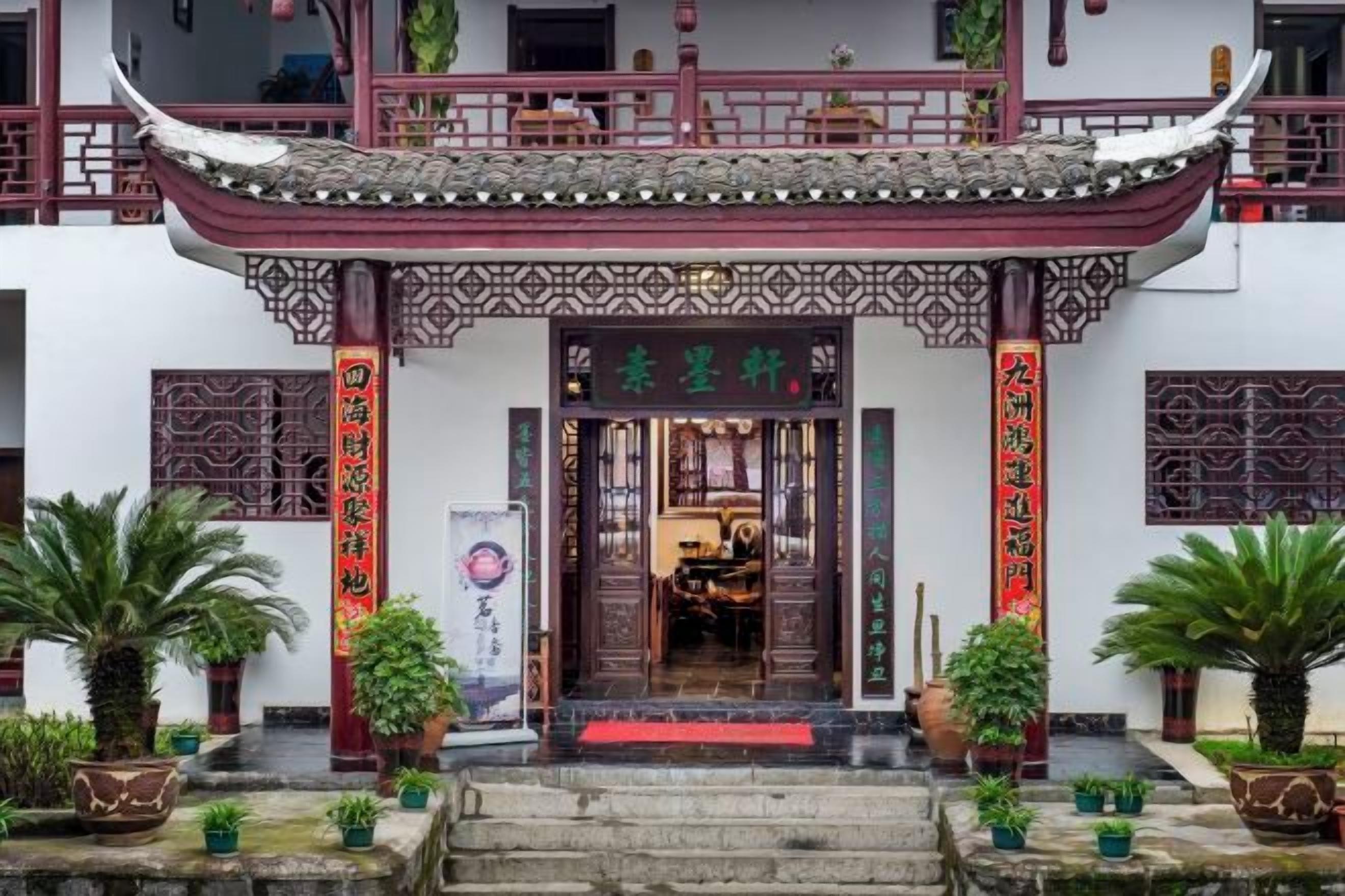 Un bâtiment traditionnel chinois, avec un toit recouvert de tuiles rouges et des portes en bois richement décorées.