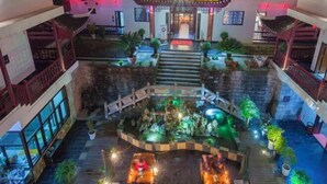 A multi-level hotel atrium with a central courtyard, balconies, and a staircase leading to the upper floors. - Biancheng Gushi Theme Culture Hotel (Yongshun)