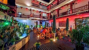 A multi-level indoor courtyard with wooden flooring, potted plants, and traditional Chinese lanterns. - Biancheng Gushi Theme Culture Hotel (Yongshun)