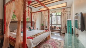 A bedroom with a four-poster bed, a glass coffee table, and a view of the outdoors. - Biancheng Gushi Theme Culture Hotel (Yongshun)